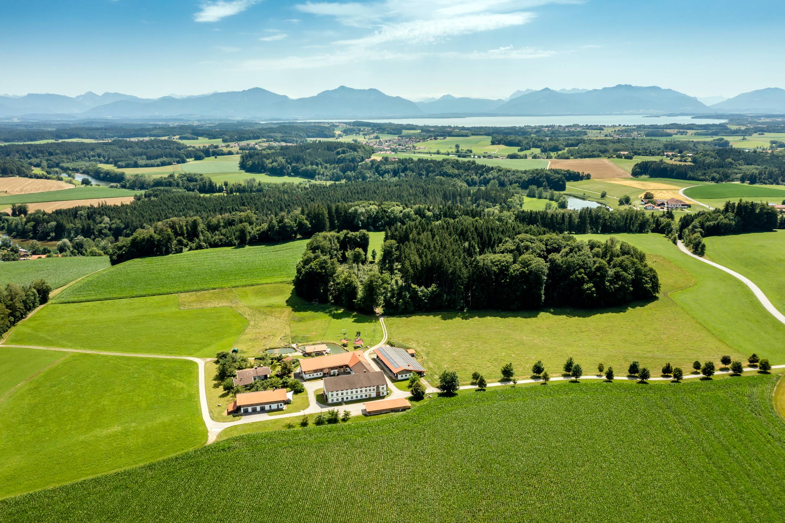 Der Staller Ferienhof von Oben mit dem Chiemsee im Hintergrund