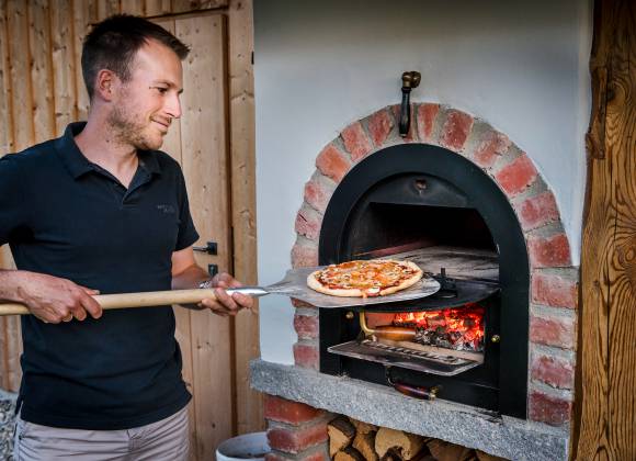 Thomas Staller backt ein Pizza im Steinofen