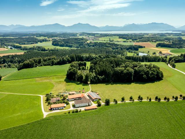 Der Staller Ferienhof von Oben mit dem Chiemsee im Hintergrund