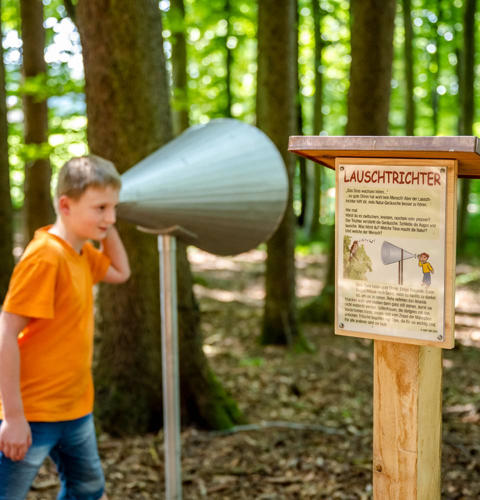 Junge probiert den Lauschtrichter im Wald aus