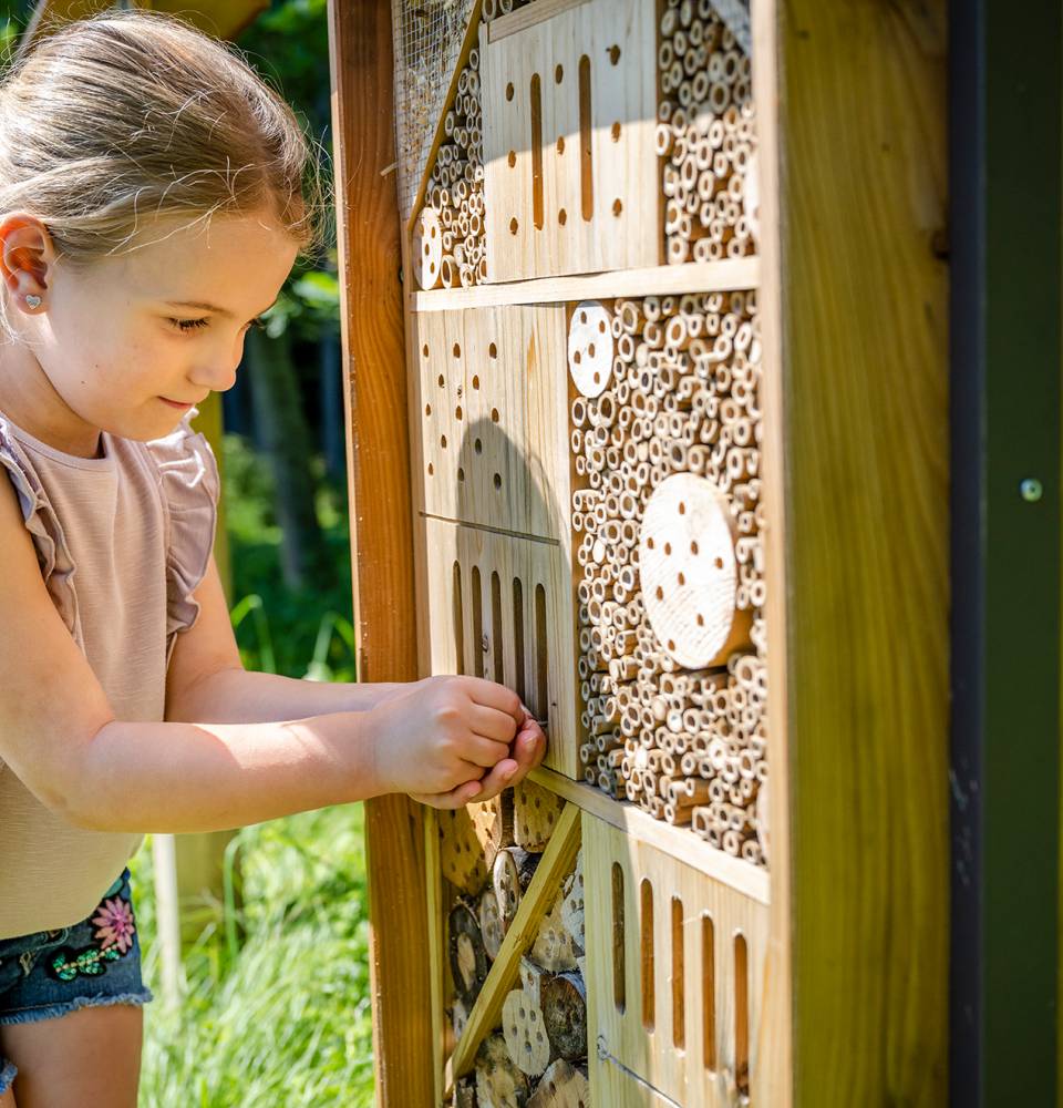 Mädchen untersucht ein Insektenhotel