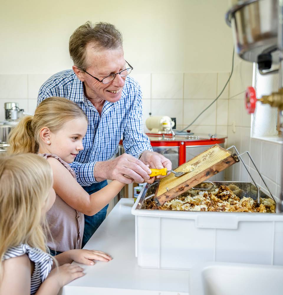 Imker zeigt Mädchen wie Honig gemacht wird