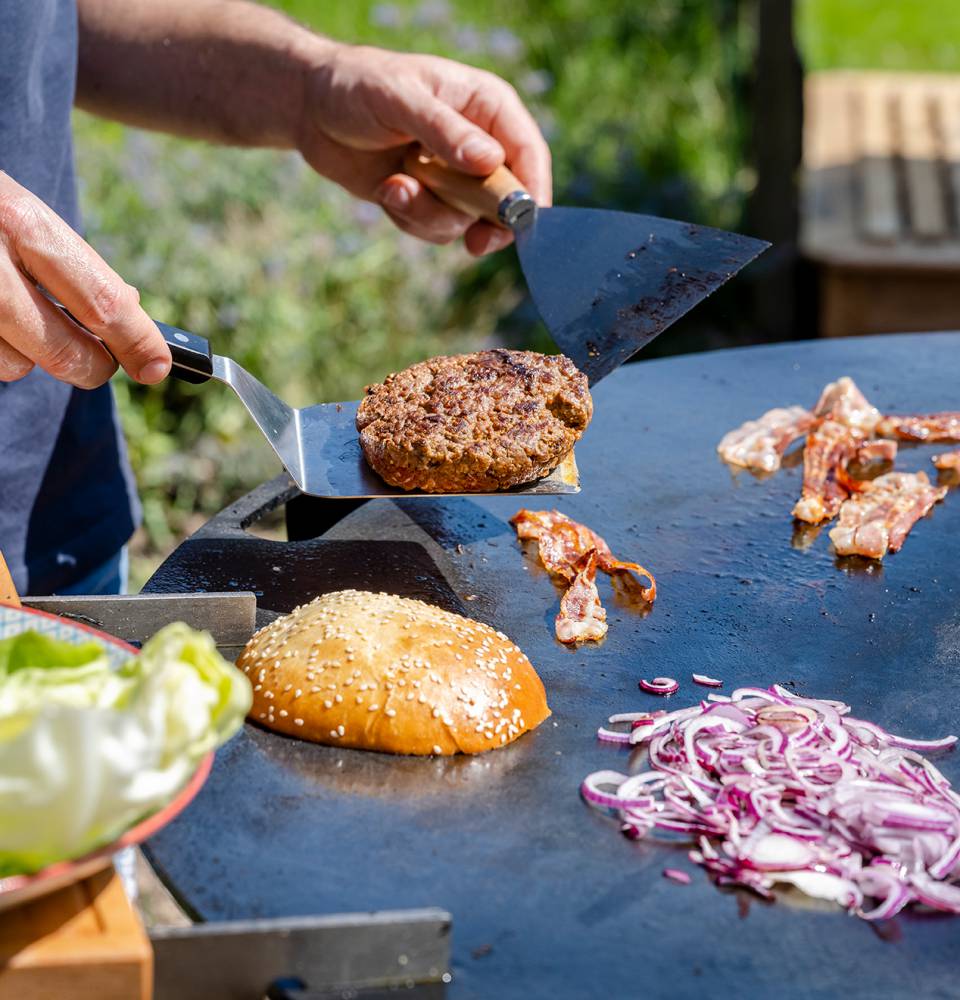 Ein Burger wird auf der heißen Platte im Freien gebraten