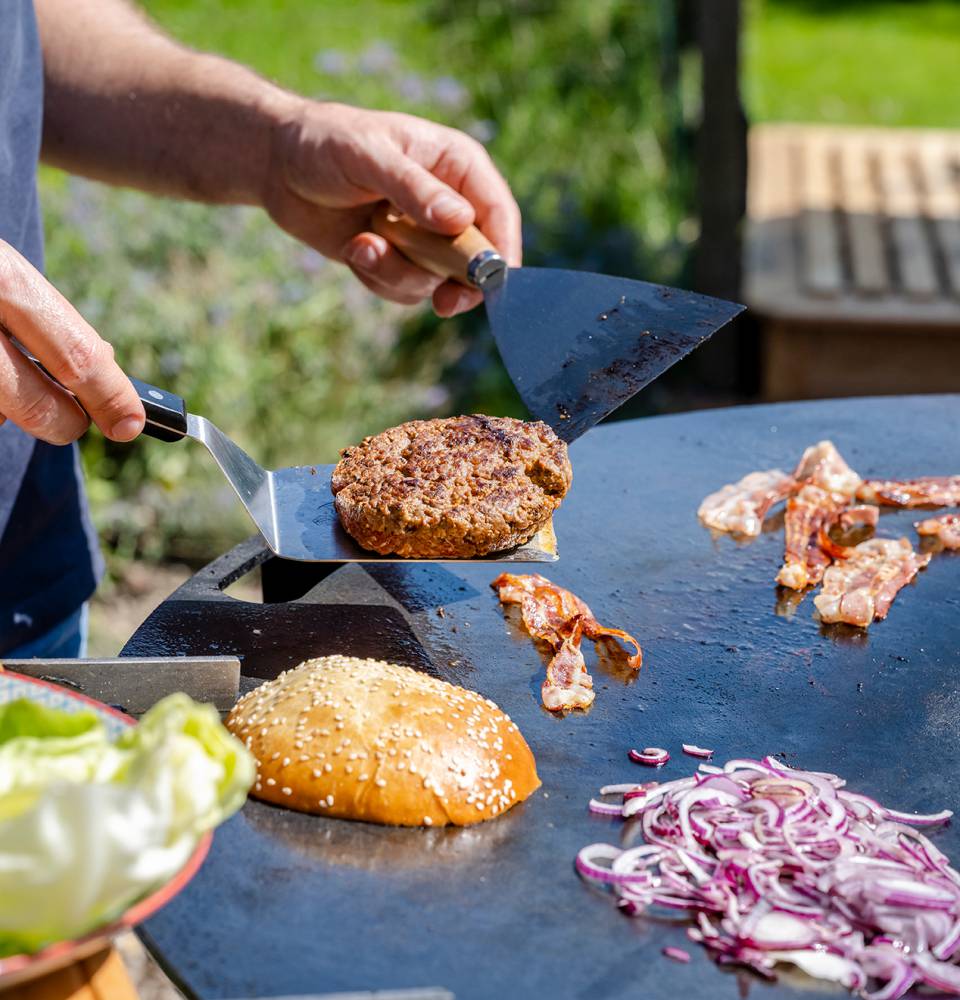 Burger und Zutaten werden auf einer Heißen Platte im Freien gebraten