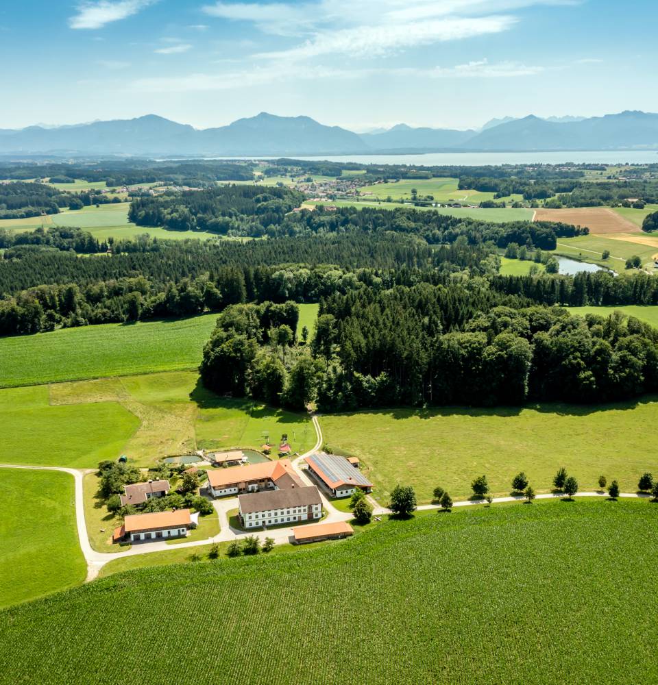 Der Staller Ferienhof von Oben mit dem Chiemsee im Hintergrund